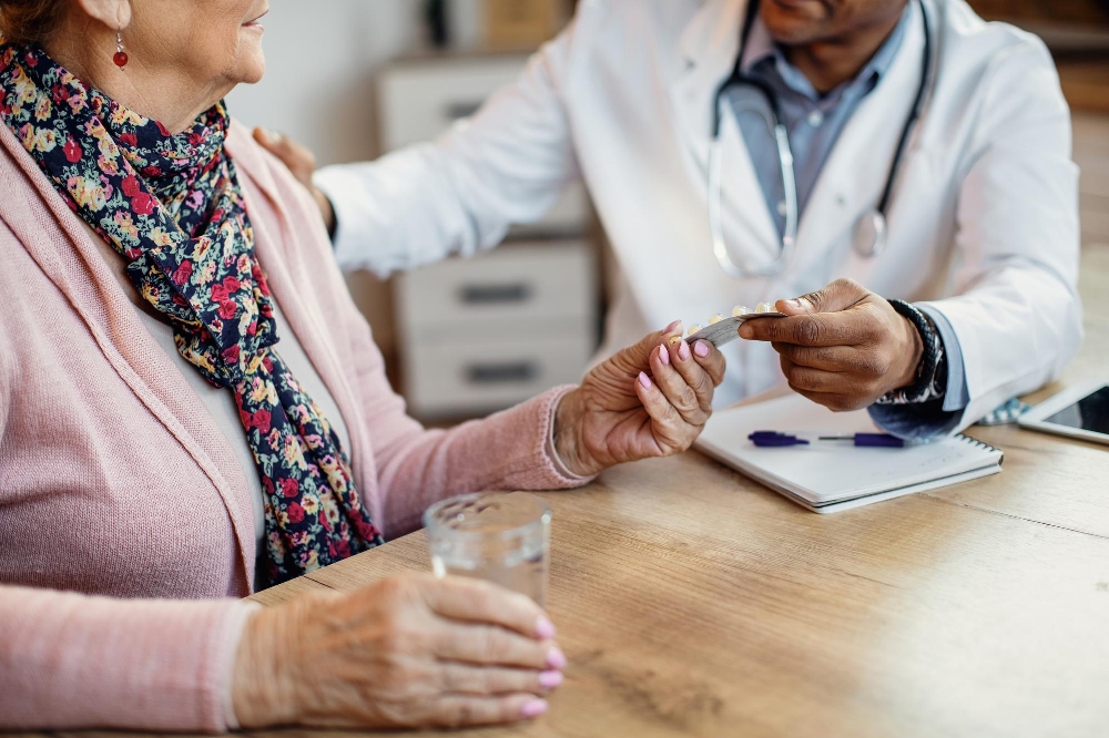 A doctor giving medication to a senior woman during a home health visit.
